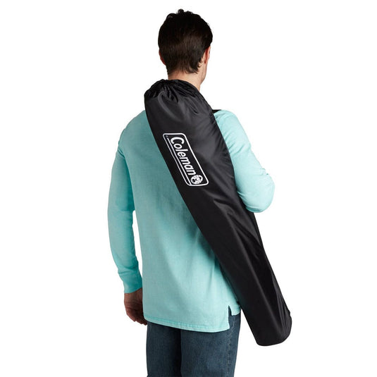 Person carrying a black Coleman travel bag on a white background