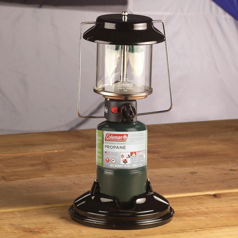 Load image into Gallery viewer, Coleman propane lantern on a wooden surface with a gray background
