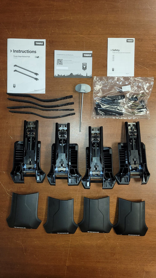 Set of black plastic components and tools on a wooden surface with instructions and safety cards.