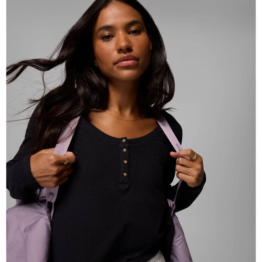 Woman holding a light purple jacket against a gray background