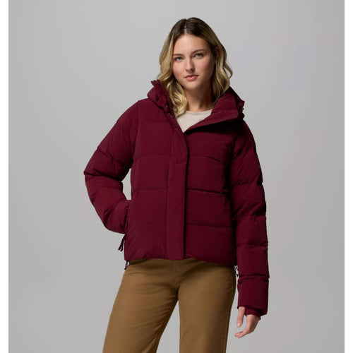 Woman wearing a maroon puffer jacket on a gray background