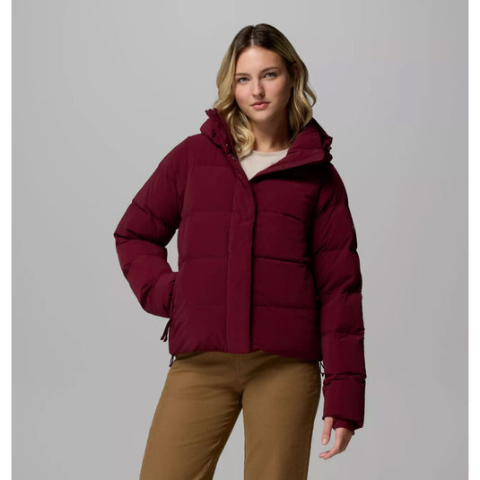 Woman wearing a maroon puffer jacket on a gray background