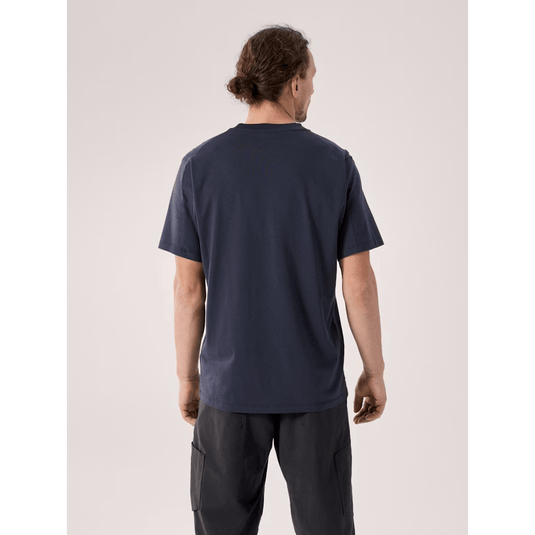 Man wearing a navy blue t-shirt and dark pants on a light gray background