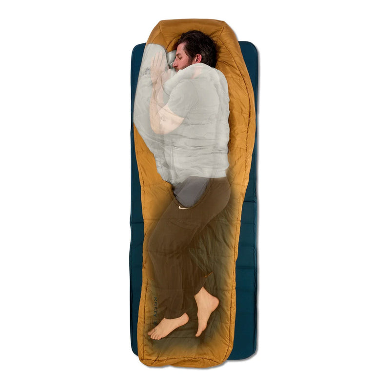 Load image into Gallery viewer, Person lying in a mustard yellow sleeping bag on a blue sleeping pad against a white background
