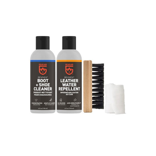 Two bottles of Rev'it boot and shoe cleaner and leather water repellent, a brush, and a cloth on a white background.
