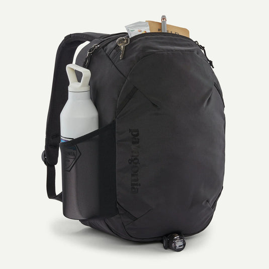 Black backpack with a water bottle and small items on a white background