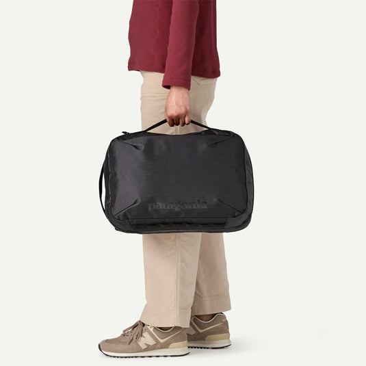 Person holding a black duffel bag with Patagonia branding on a white background