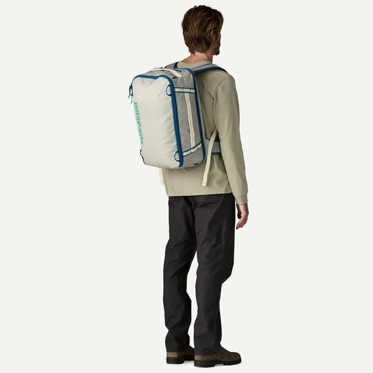 Person wearing a large white patagonia backpack with blue accents on a white background