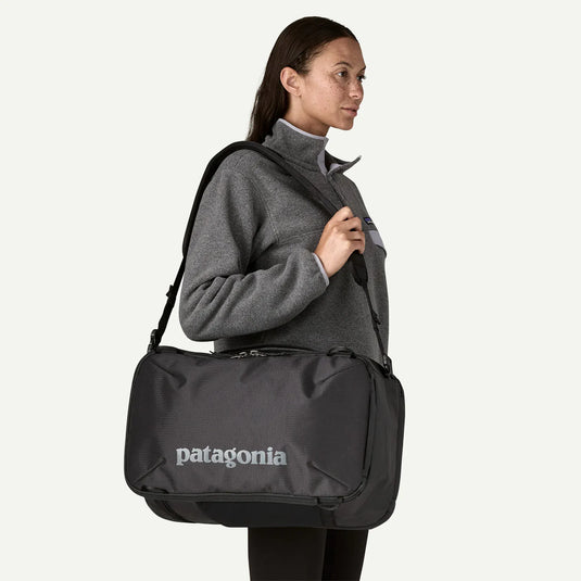 Person carrying a black Patagonia bag on a white background
