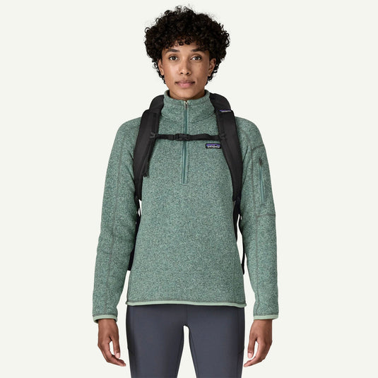 Person wearing a green fleece pullover with a black backpack on a white background