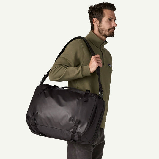 Man carrying a black duffel bag on a white background