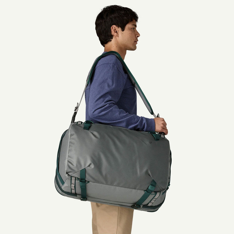 Load image into Gallery viewer, Person carrying a gray duffel bag with green straps on a white background
