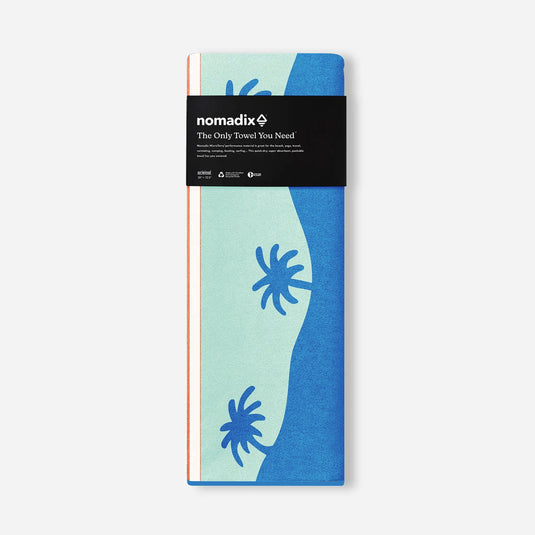 Packaged towel with blue and green design and 'nomadix' branding on a white background