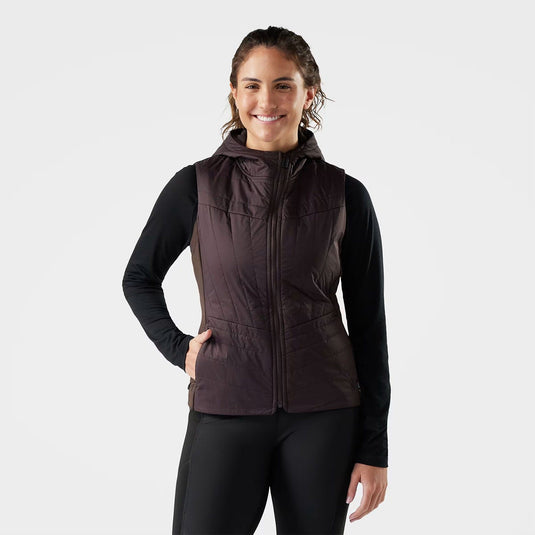 Woman wearing a brown quilted vest over a black long-sleeve shirt on a white background