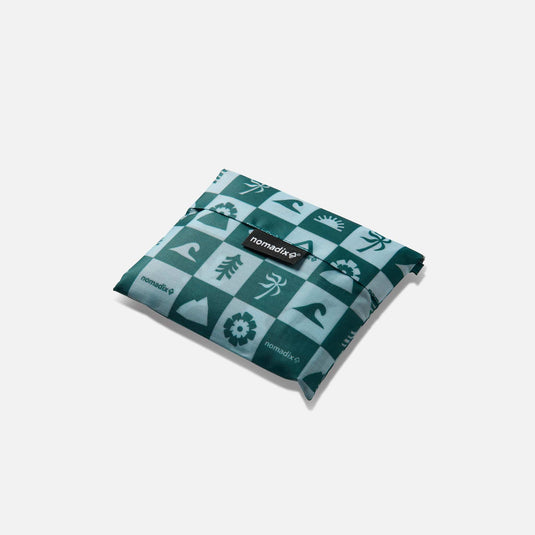 Folded teal fabric with pattern and 'nomadix' branding on a white background