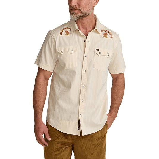 Man wearing a beige short-sleeve shirt with floral embroidery on a white background