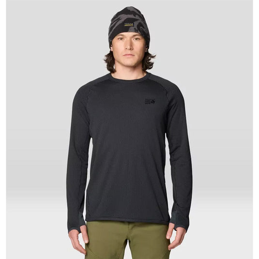 Man wearing a black long-sleeve shirt, green pants, and a black beanie with a logo on a light gray background