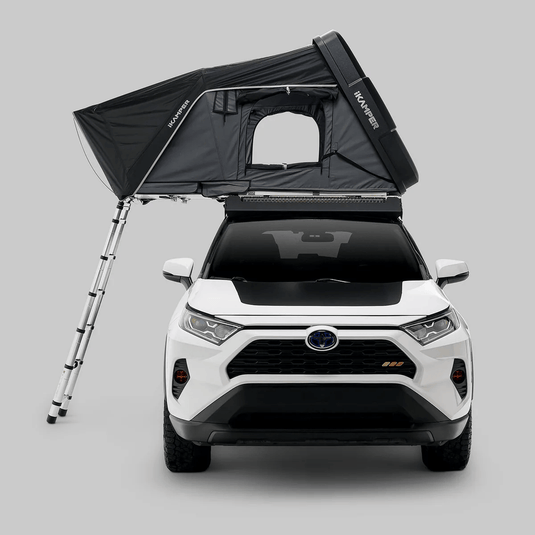 White SUV with a black rooftop tent on a gray background