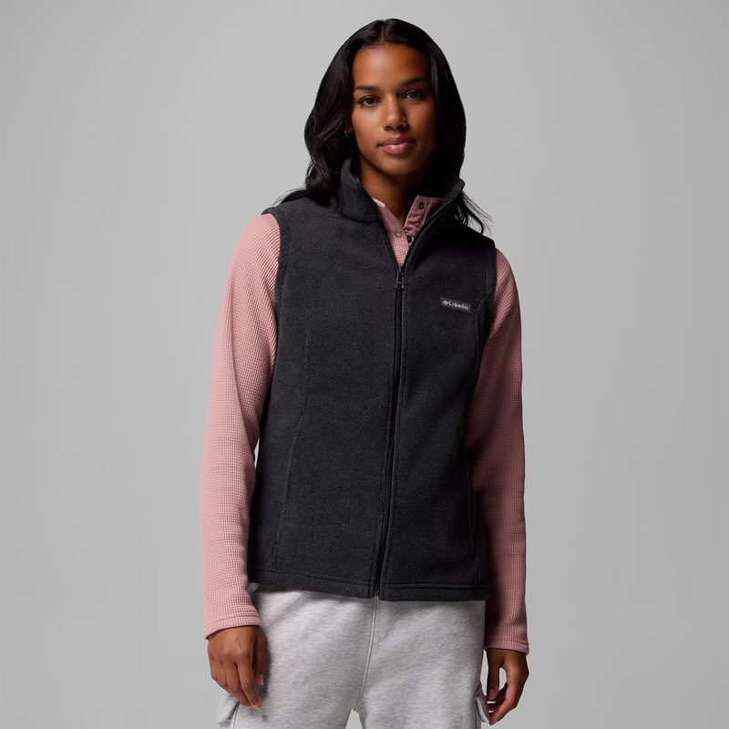 Load image into Gallery viewer, A woman modeling a dark charcoal fleece vest over a dusty pink long-sleeve shirt and light gray sweatpants, photographed against a solid gray studio background.

