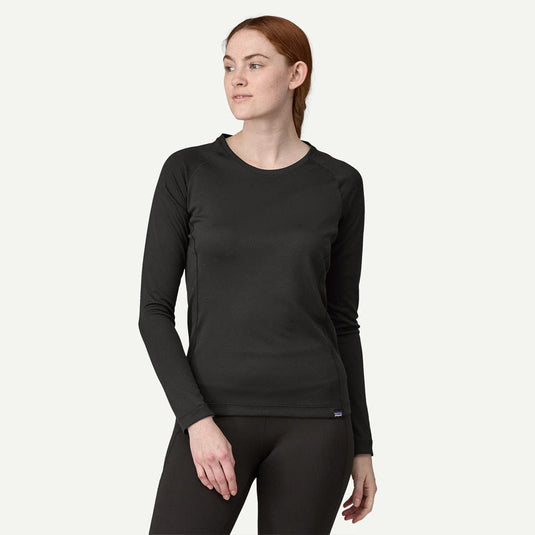 Woman wearing a black long-sleeve top and pants on a white background