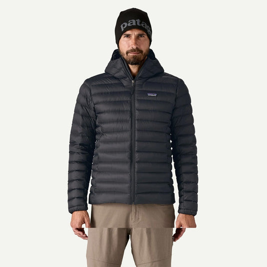 Man wearing a black puffer jacket and beanie with 'patagonia' branding on a white background
