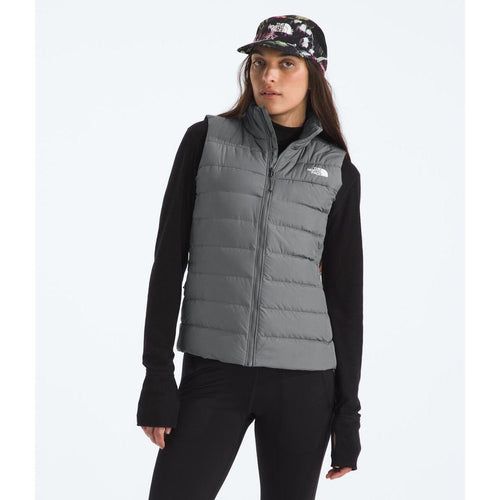 Woman wearing a gray puffer vest with a brand logo on a white background
