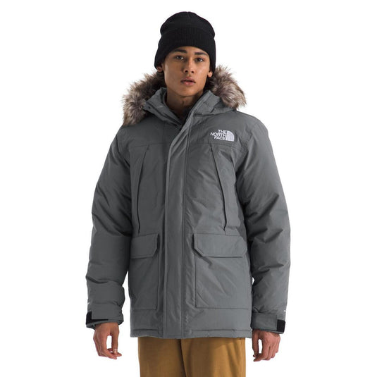 Person wearing a gray winter jacket with fur hood and The North Face logo on a white background