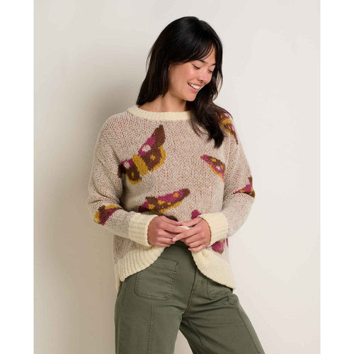 Woman wearing a sweater with butterfly patterns against a plain background