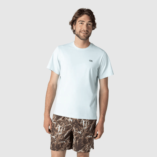 Man wearing a light blue t-shirt and camouflage shorts on a white background
