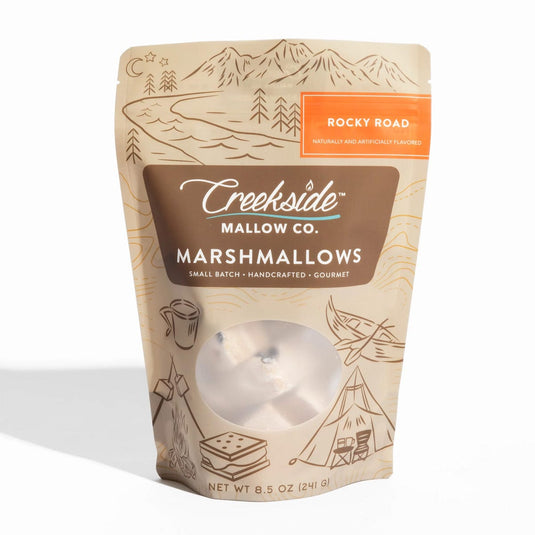 Packaging of Creekside Mallow Co. marshmallows with mountain and camping illustrations on a white background.