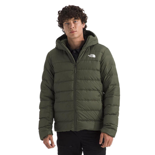 Person wearing a green puffer jacket with a brand logo on a white background