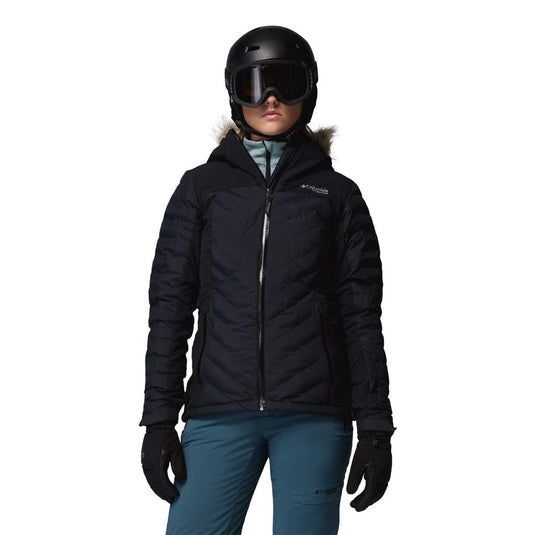 Person wearing a black winter jacket, helmet, and goggles on a white background