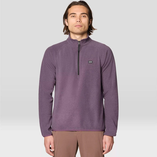 Man wearing a purple pullover with a small logo on a light gray background