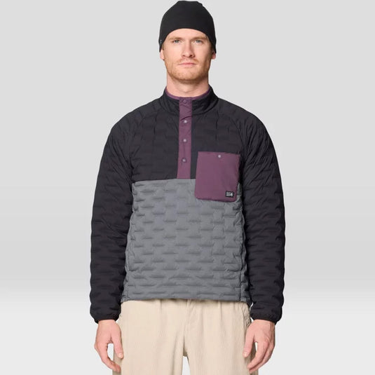 Man wearing a black and gray quilted jacket with a purple pocket on a light gray background