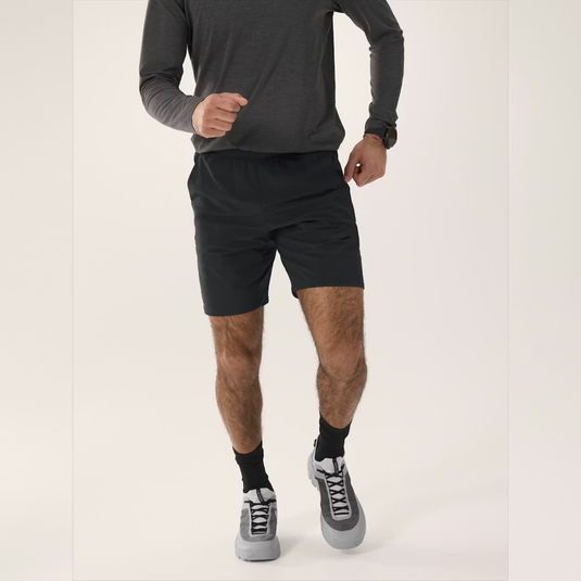 Person wearing black athletic shorts and gray sneakers on a white background