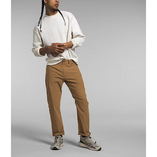 Person wearing a white long-sleeve shirt and brown pants on a gray background