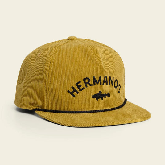 Yellow cap with 'HERMANOS' text and fish logo on a beige background