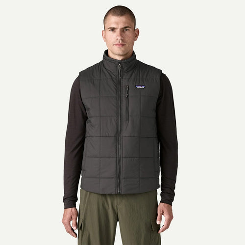 Man wearing a dark gray puffer vest with a brand logo on a white background