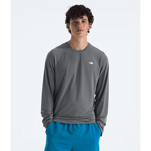 Person wearing a gray long-sleeve shirt with a logo and blue shorts on a white background