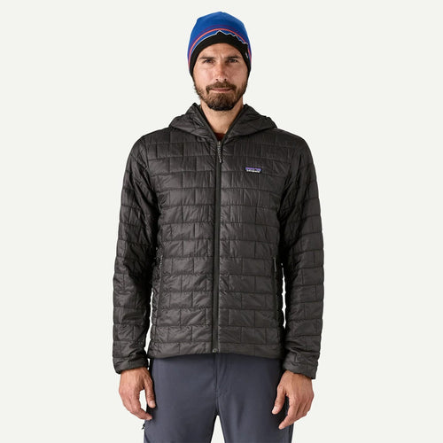 Man wearing a dark gray quilted jacket and blue beanie on a white background