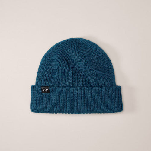 Blue knit beanie with a brand logo on a beige background