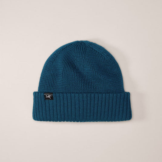 Blue knit beanie with a brand logo on a beige background