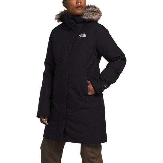 Person wearing a black coat with fur hood on a white background