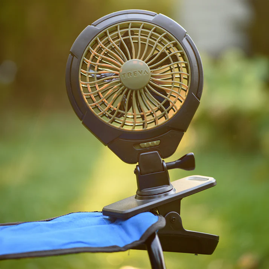 Portable fan with a clip on a blue surface against a blurred green background