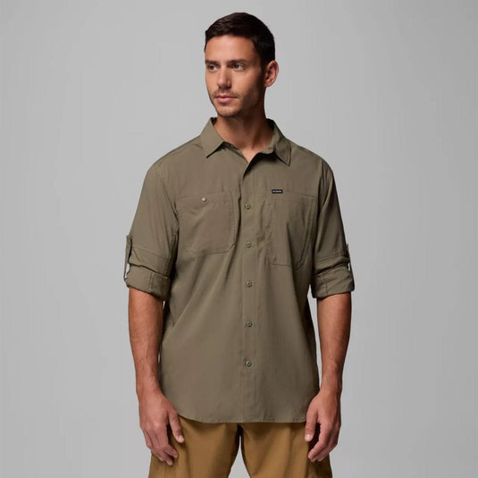 Man wearing a green shirt with rolled-up sleeves against a gray background