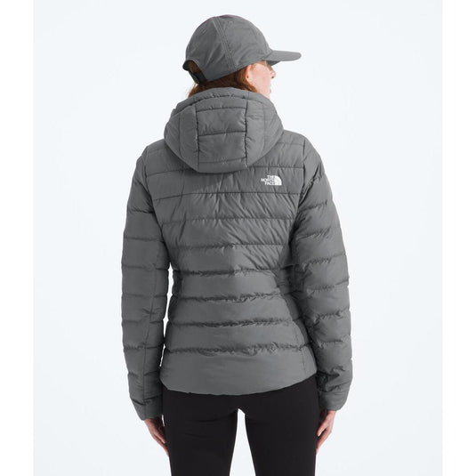 Person wearing a gray puffer jacket with a hood on a white background