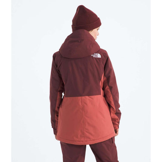 Person wearing a two-tone red and brown jacket with a visible brand logo on a white background