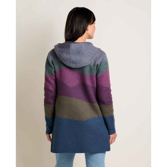Person wearing a colorful striped coat on a plain background