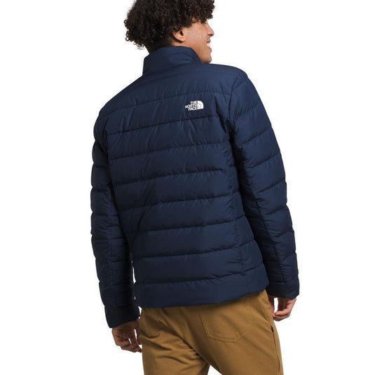 Person wearing a navy blue puffer jacket with The North Face logo on a white background