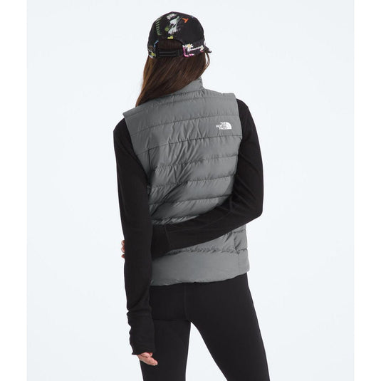 Person wearing a gray puffer vest with a visible brand logo on a white background